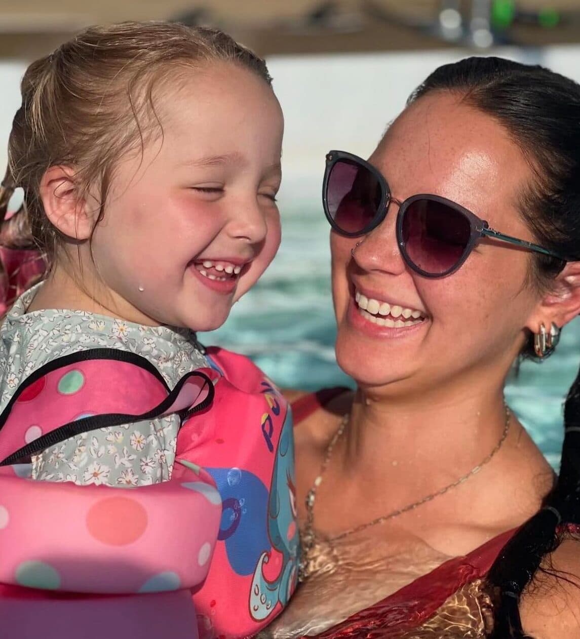 a mom holding her daughter in the pool